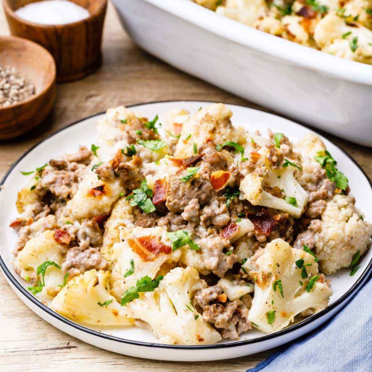 a flat white dish with a blue rim filled with beef and cauliflower casserole