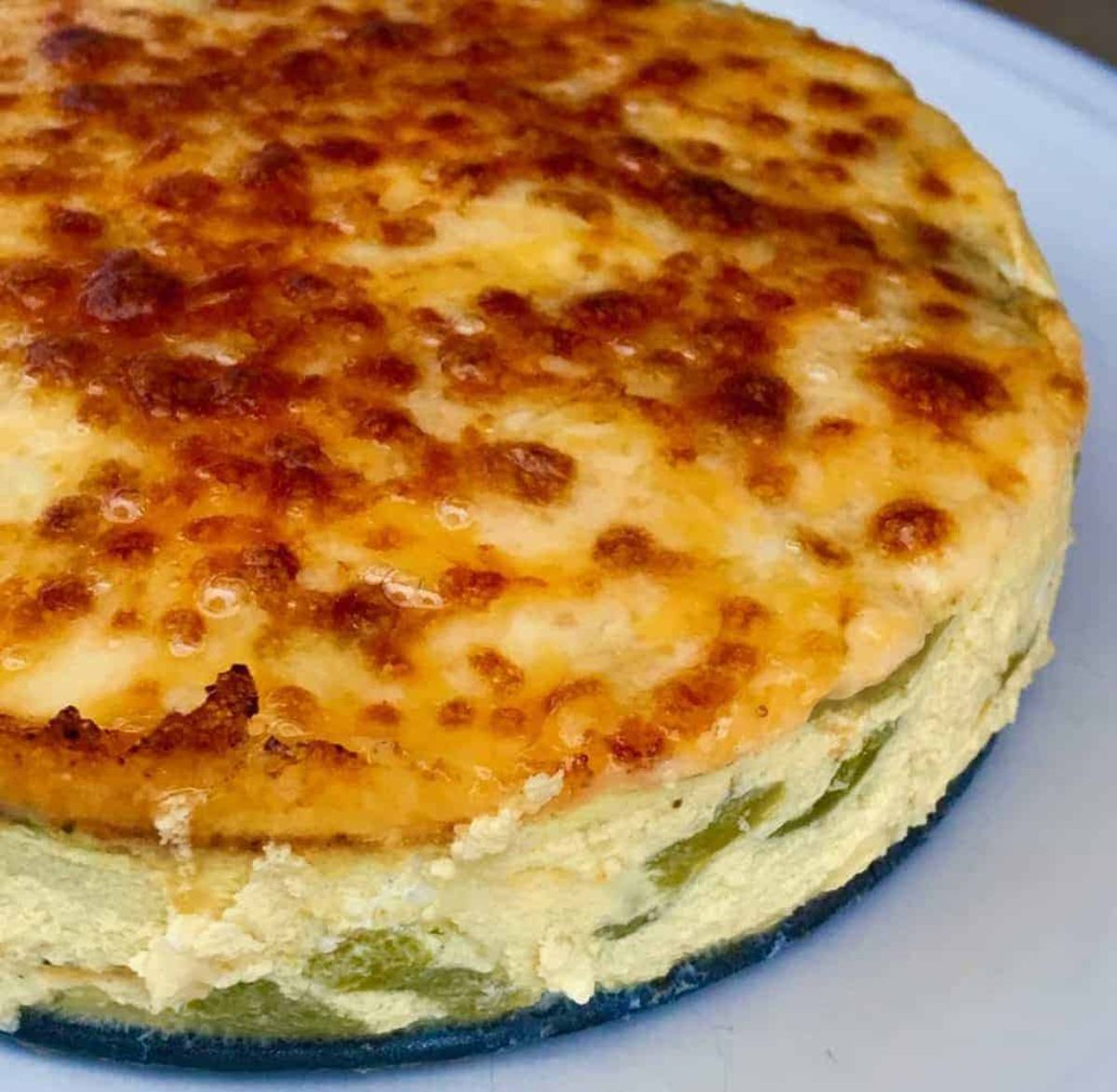 a partial shot of a fritatta with green beans in it and a caramalised cheese top