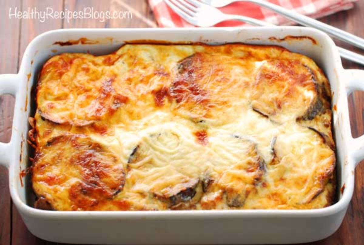 a rectangular casserole dish with aubergine and white sauce layers and a cheesy top