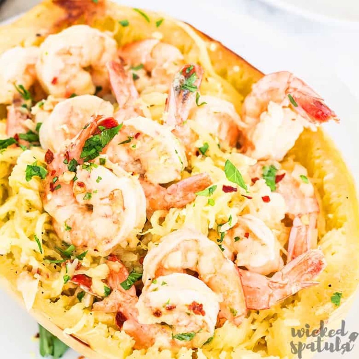 A hollowed out spaghetti squash filled with spaghetti squash, shrimp and chopped herbs