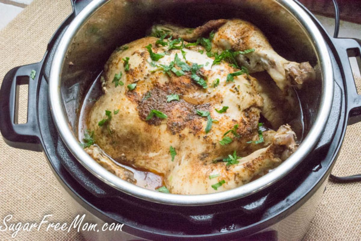 On a hessian cloth is an instant pot with a whole chicken inside, sitting in gravy and scattered with parsely