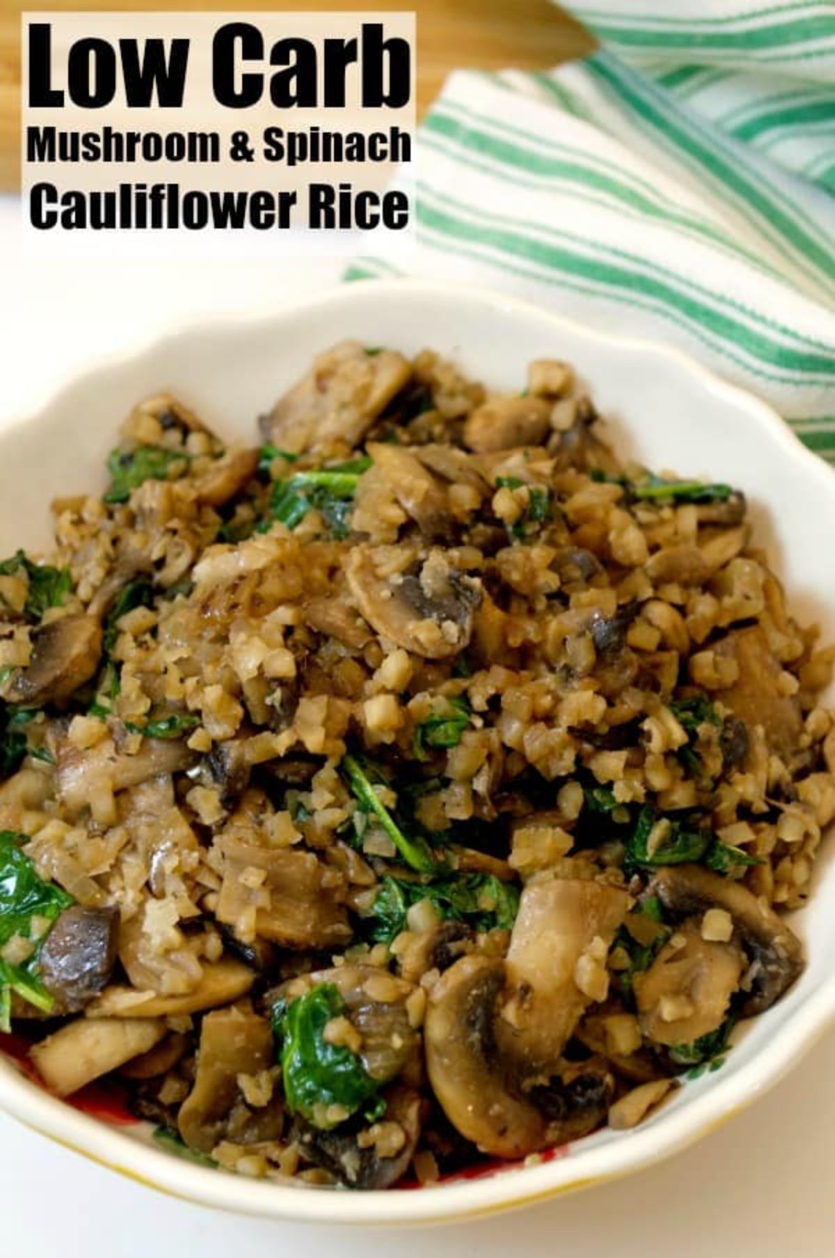 The text reads "Low Carb Mushroom & Spinach Cauliflower Rice". A white round bowl is filled with mushrooms, spinach and cauliflower rice. Behind is a blurred green and white striped towel