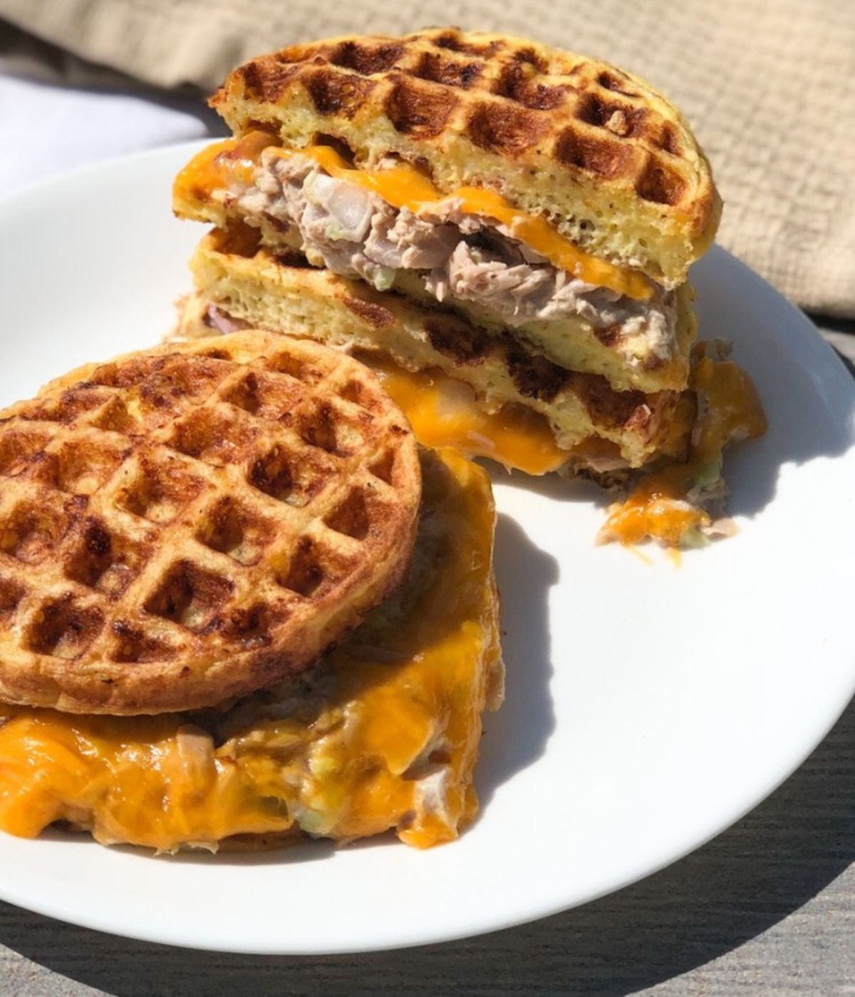 A white plate holds stacks of waffles filled with cheese and tuna