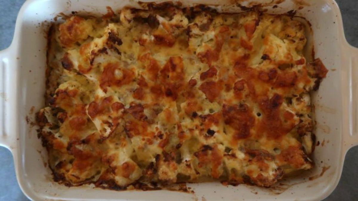 A rectangular white casserole dish holds a cheese-topped casserole