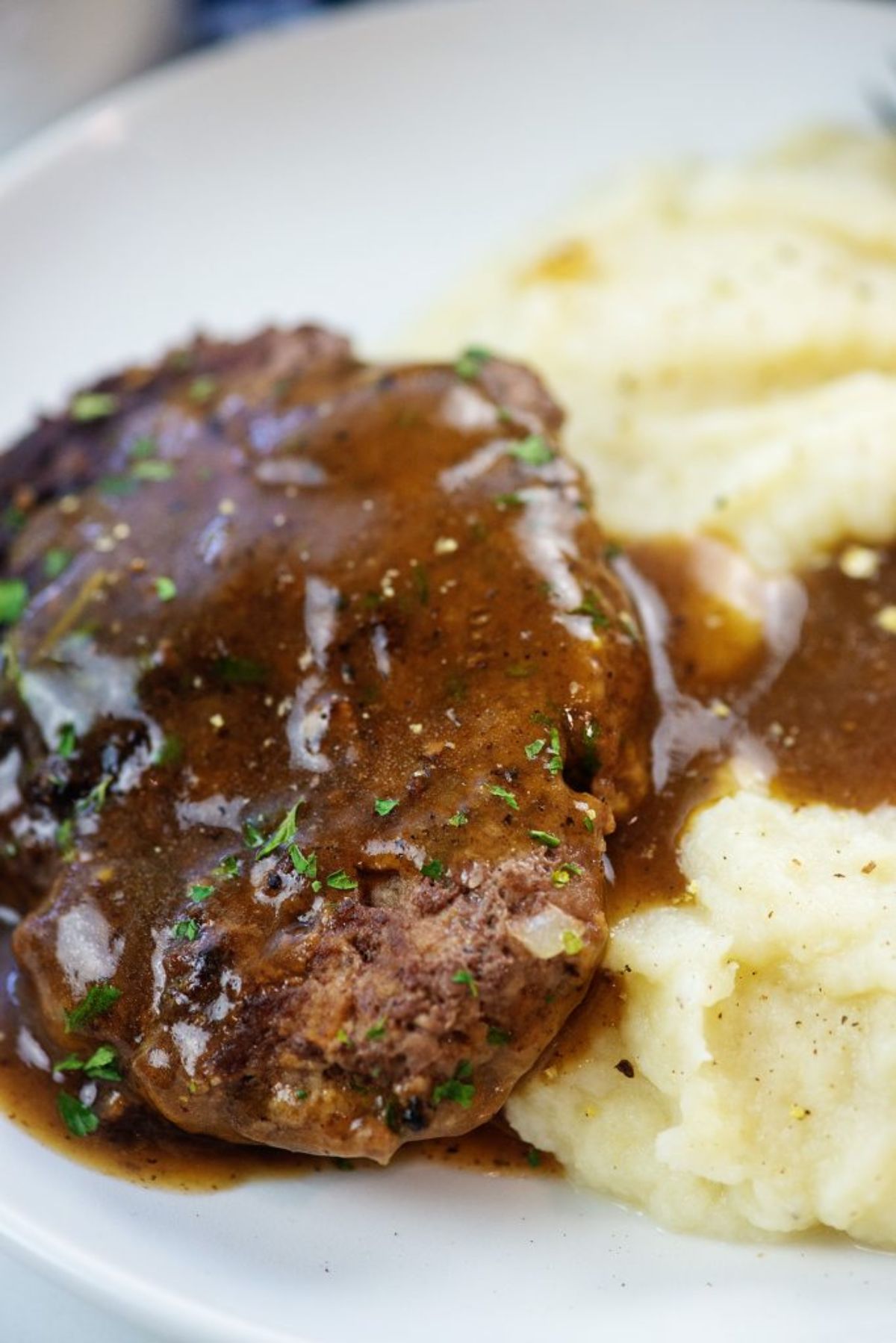 A partial close up of a steak in gravy, and mashed potato