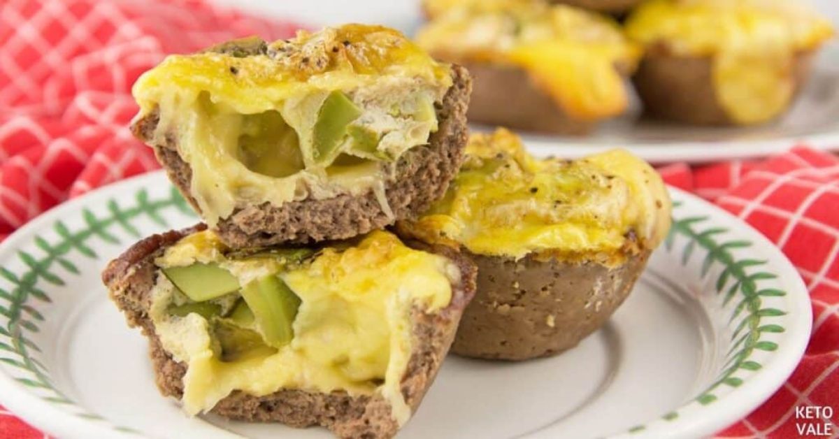 on a red and white tablecloth is a white plate with a green leaf pattern around the edge. 3 muffins, with 2 cut open, are stacked on the plate.