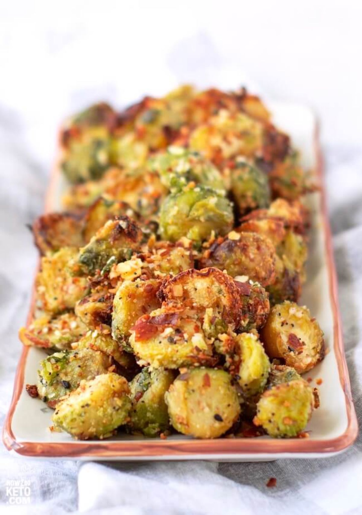 A rectangular serving platter filled with cheesy brussel sprouts