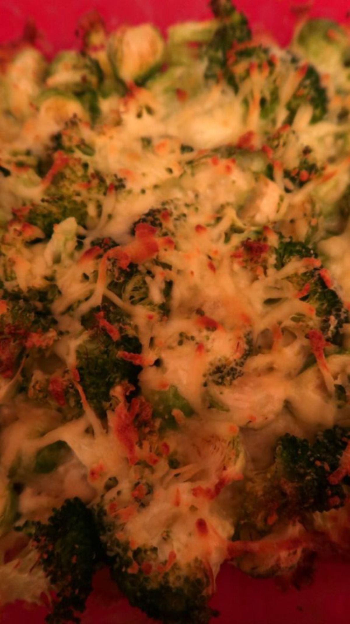 A section of a cheesy broccoli casserole in a red dish