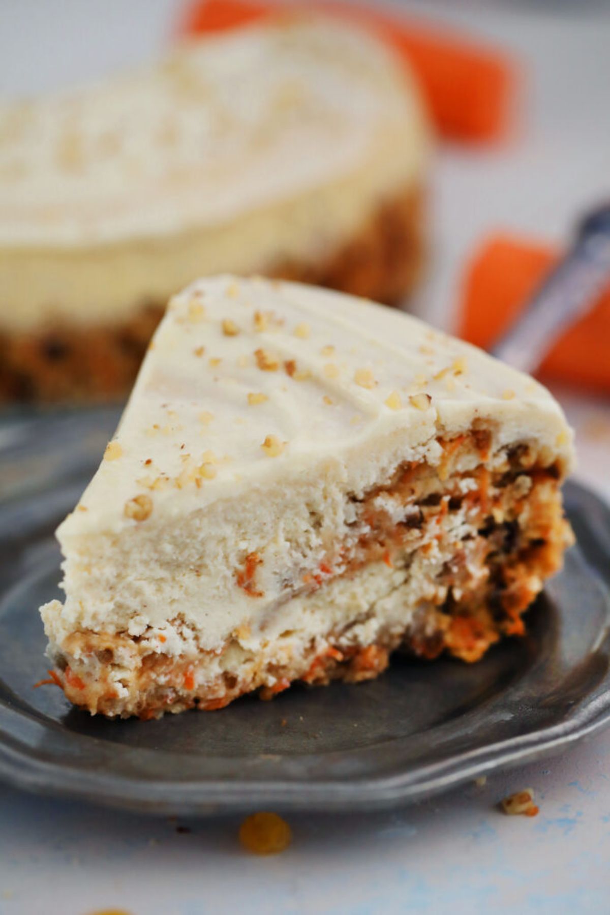 A carriot cake cheesecake slice on a dark plate