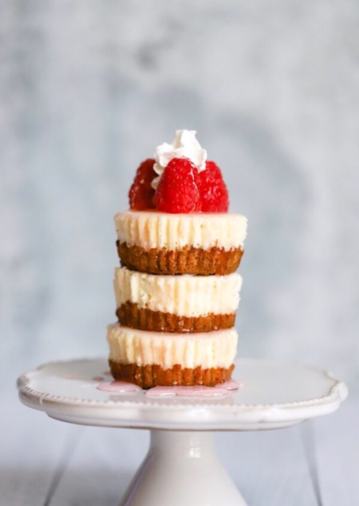 A stack of 3 cheesecake bites with strawberries and cream on top