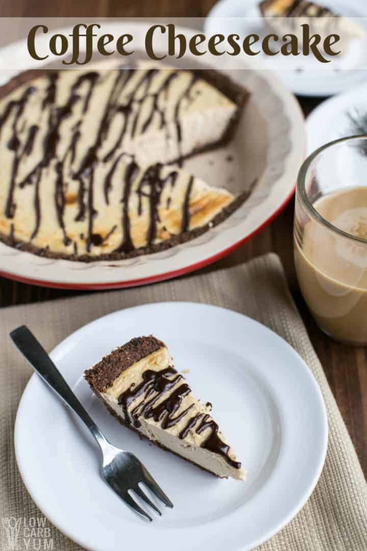 In front of a pie dish containing a vanilla cheesecake with chocolate drizle is a slice of the cheesecake on a plate with a fork