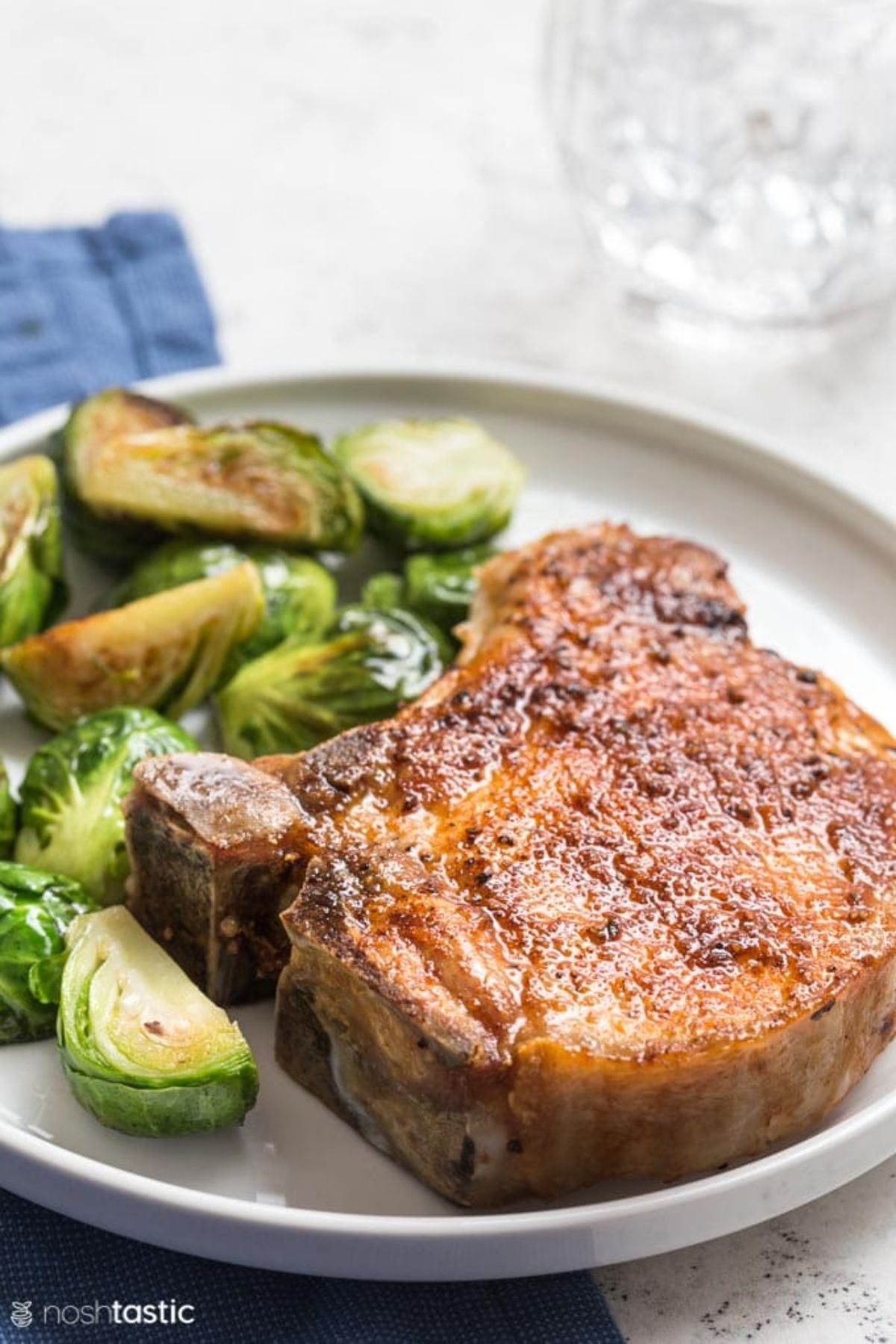 A round white pplate contains cooked chopped brussel sprouts and a pork chop