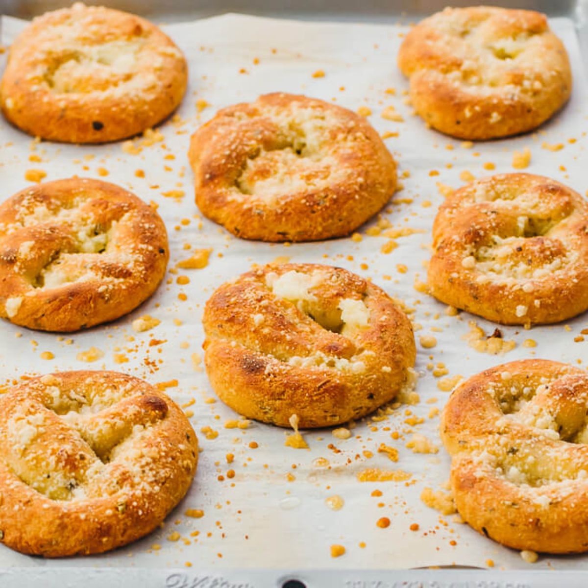 On a baking sheet are 8 round twisted rolls sprinkled with cheese